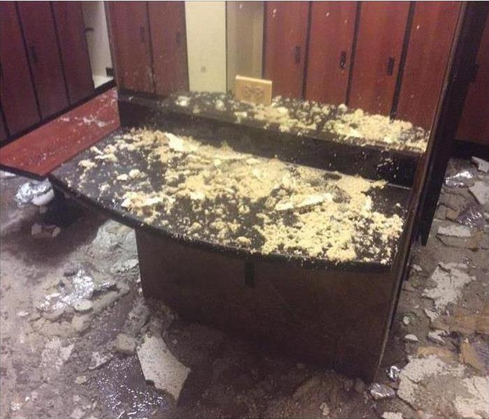 Counter in a locker room covered with debris with lockers in the background.