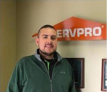 SERVPRO employee standing in front of a SERVPRO sign.