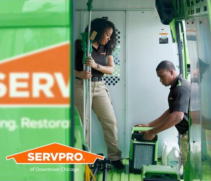 SERVPRO Professionals are loading equipment into a SERVPRO vehicle.