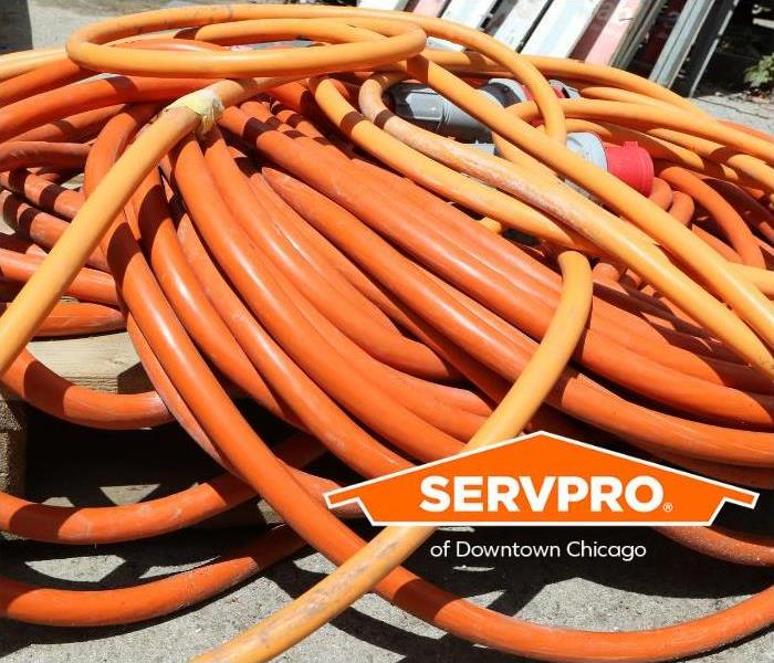 A pile of orange extension cords lay on the ground.