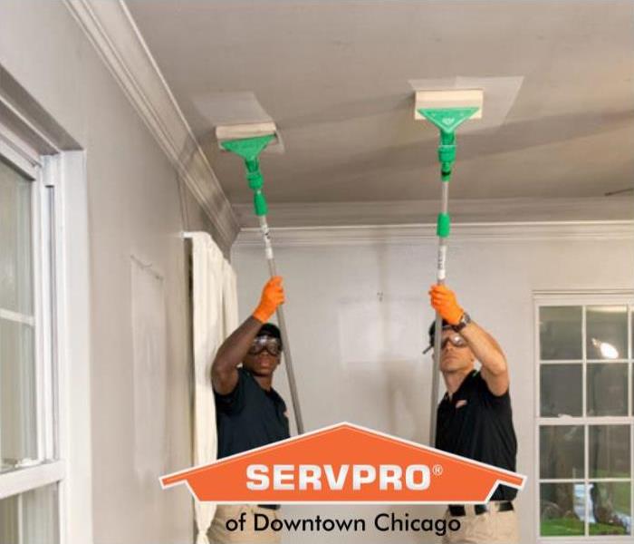 Two SERVPRO employees cleaning soot off the ceiling.